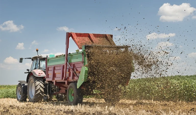 Traktor som sprider fjäderfägödsel.