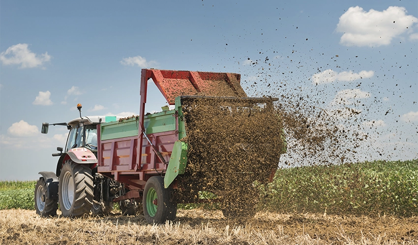 Traktor som sprider fjäderfägödsel.